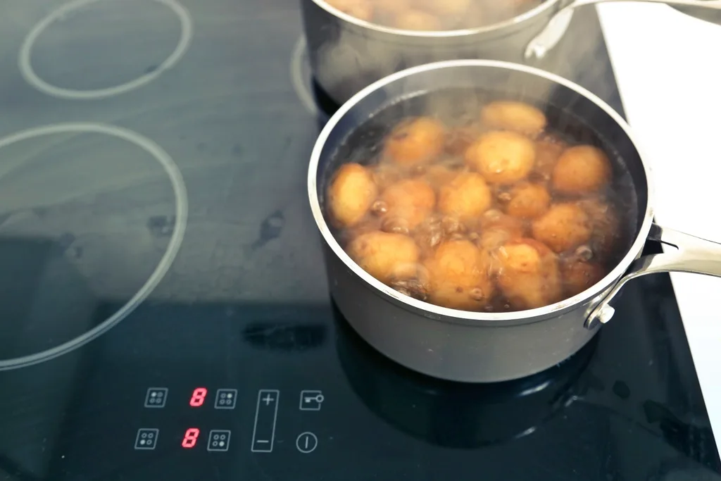 Pots cooking on a multi-zone induction cooktop, seen from above